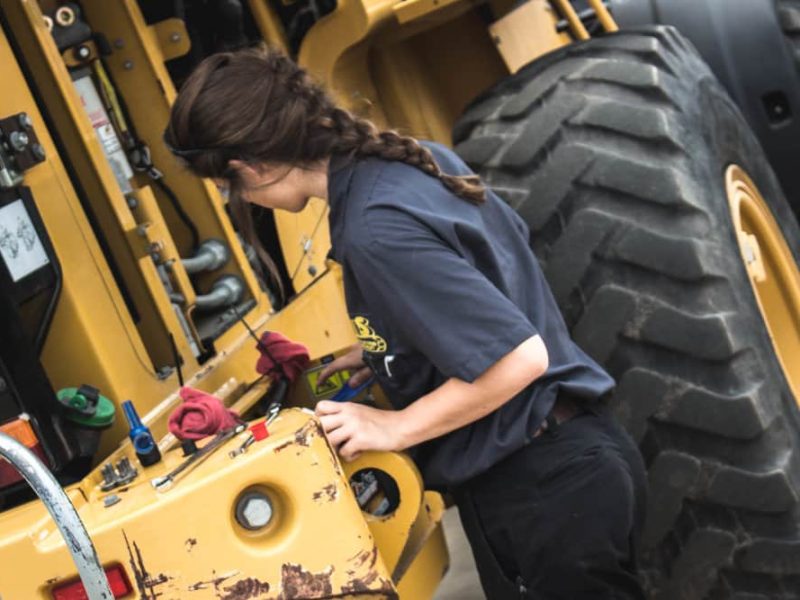 Woman inspecting construction vehicle