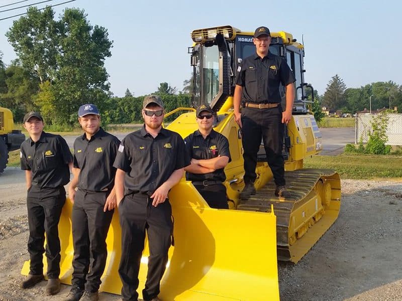 Students standing in front of dozer